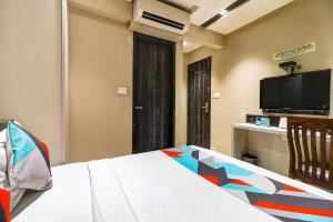 孟买FabHotel Grand Heritage Kurla West的一间卧室配有一张床和一台平面电视