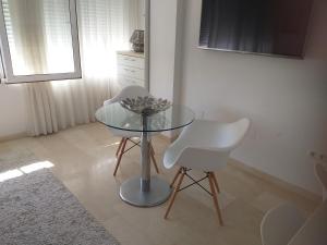 阿利坎特Estudio Playa del Postiguet的玻璃桌和两张白色椅子