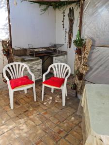 开普敦Angel's Corner的庭院里配有两把白色椅子和红色靠垫