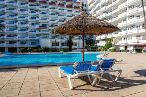 阿尔库迪亚港Apartamento Villa Cancun的游泳池旁的两把椅子和一把遮阳伞
