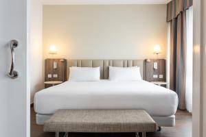 拉科鲁尼亚Eurostars Atlántico的卧室配有白色大床和长凳