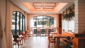 达叻府Li CALLA Resort Trat的餐厅设有木桌、椅子和窗户。