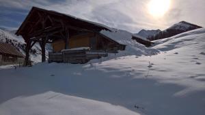 LongefoyHôtel et Appart'Hôtel Restaurant L'Adray的雪中的一个小屋,后面是太阳