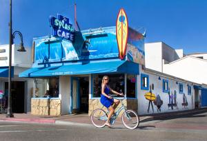 皮斯莫比奇海上冒险海滩酒店的一名妇女在冲浪咖啡馆前骑着自行车