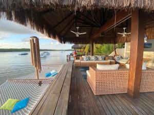 伊波茹卡Casa praia Porto de Galinhas Toquinho的木质甲板上的带桌椅的度假酒店