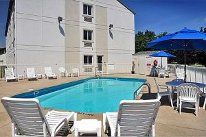 米兰诺桑达斯基米兰6号汽车旅馆的一座带椅子和遮阳伞的游泳池位于一座建筑旁边