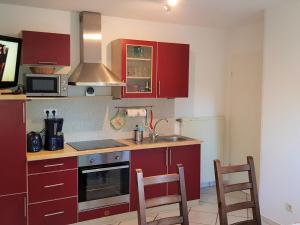 齐罗Ostsee 1的厨房配有红色橱柜、水槽和2把椅子