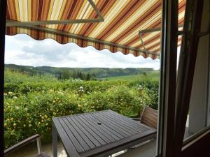 Boevange-ClervauxCozy Holiday Home in Boevange Clervaux with Garden的一个带桌子的门廊,享有花田的景色