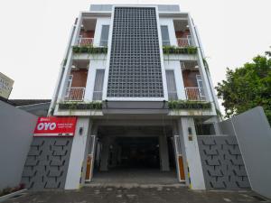 日惹Super OYO Collection O 90023 Damar Kusumo Guest House的一座高大的白色建筑,设有停车库