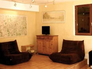 Saint-Jean-de-Thurigneux莱斯巴利里斯酒店的客厅配有两把椅子和电视