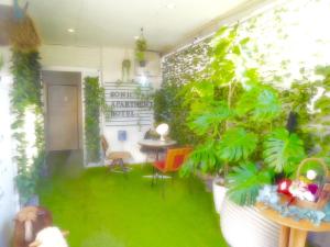 太宰府市SONIC APARTMENT HOTEL的一间拥有绿色植物和桌椅的房间