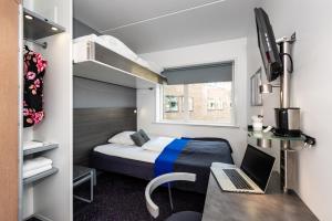 哥本哈根卡宾城市酒店的小房间设有一张床和一张带笔记本电脑的书桌