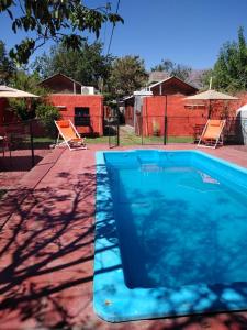 卡法亚特Cabañas y Hostal Las Marias的蓝色游泳池,带两把椅子和围栏
