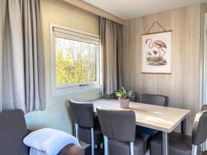 东卡佩勒Familie Chalet Oostkapelle OK30的一间带桌椅和窗户的用餐室