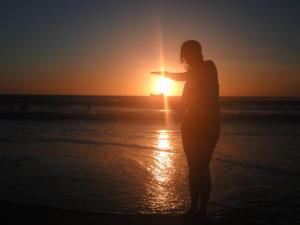 卡波布里奥Apartamento Jamesson Cabo Frio的一位站在海滩上观看日落的女人