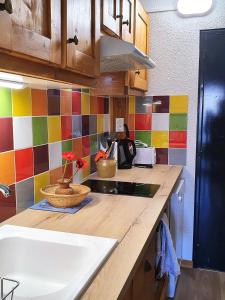 圣莫里斯堡les 3 marmottes - Les Arolles的厨房配有带水槽和彩色瓷砖的柜台。