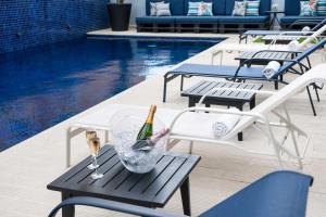 维多利亚维多利亚港金色郁金香酒店的一个带桌子的游泳池,配有两瓶葡萄酒和眼镜