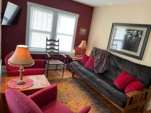 戴德伍德1899号住宿加早餐旅馆的客厅配有黑色沙发和红色椅子