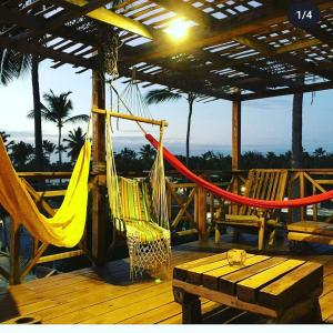 蓬塔卡纳Hostel Eco Punta Cana的甲板上的吊床,配有桌子和长凳
