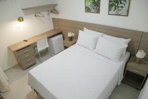嘎林海斯港Flats Angatu Porto de Galinhas PE的卧室配有一张白色大床和一张书桌