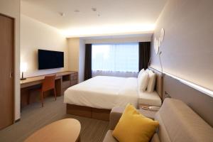 大阪Holiday Inn & Suites Shin Osaka, an IHG Hotel的酒店客房设有一张床、一张书桌和一台电视机。