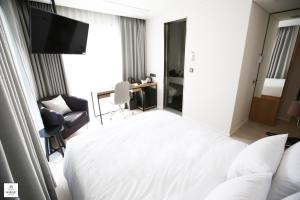 釜山Londoner Hotel Gwangan的酒店客房,配有白色的床和椅子