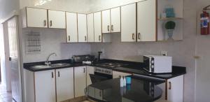 马盖特Dumela Margate Flat No 18的厨房配有白色橱柜和黑色台面