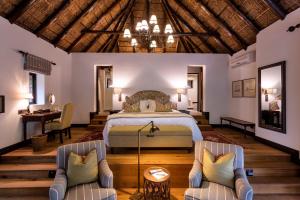 帕特森Lalibela Game Reserve - Kichaka Lodge的一间卧室配有一张床和两把椅子
