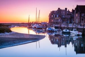 布莱克尼Blakeney Norfolk Bramble Lodge ***Self Catering***的日落时分停靠在码头的一组船