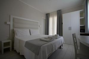兰佩杜萨La Guitgia Rooms的白色卧室,配有带毛巾的床