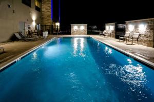 泰勒Holiday Inn Express & Suites Taylor, an IHG Hotel的夜晚的游泳池,有蓝色的水