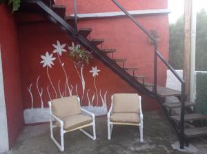 米纳斯Hosteling Las Margaritas的两把椅子坐在楼梯旁,墙上挂着壁画