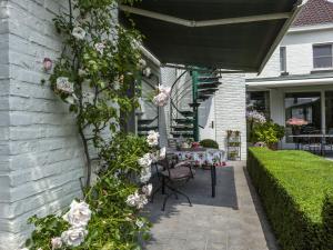 ZingemModern Holiday Home in Zingem with Garden的房屋一侧带桌子和鲜花的庭院