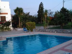 莱弗考基亚Chic Villa in Lefkogia Crete with Swimming Pool的一个带椅子和房子的游泳池