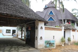 蒙巴萨Room in Guest room - A wonderful Beach property in Diani Beach Kenya的前面有标志的茅草屋顶建筑