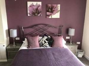 锡顿Mariners Hotel的一间卧室配有一张紫色墙壁的床和两盏灯。