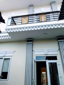土龙木市Nhà nghỉ Đế Vương的白色的房屋,设有圆柱和阳台