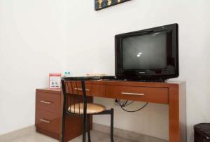 泗水Soerabaja Place Guest House的一张桌子上的电视机,椅子
