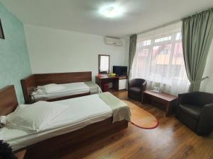 雅西Moldotour的一间卧室设有两张床、一把椅子和一个窗户。