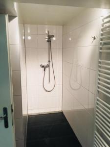 弗莱堡ruhiges privates Zimmer in Freiburg, zentrumsnah, Nähe Europapark的白色瓷砖浴室内带软管的淋浴