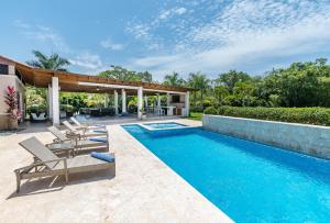 拉罗马纳Stunning Villa with Private Pool and Jacuzzi in Casa de Campo的一个带躺椅的游泳池以及一座房子