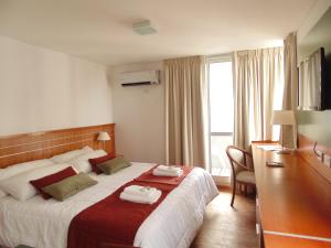 罗萨里奥卡塔马卡朗德套房公寓酒店的配有一张床、一张书桌和一扇窗户的酒店客房