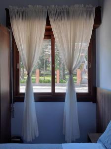 格拉玛多Suíte Lago Negro的卧室内带白色窗帘的窗户