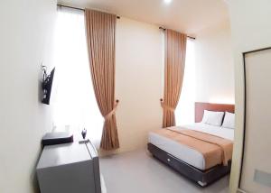 PaalmerahRedDoorz Syariah near Transmart Jambi 2的一间卧室配有一张床和一台电视