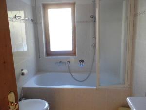 修希Villa Bernhard的带浴缸、卫生间和窗户的浴室