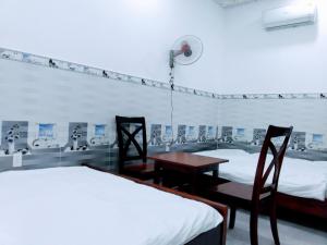 土龙木市Nhà nghỉ Đế Vương的一间设有两张床和一张桌子及椅子的房间