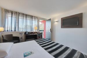 梅里尼亚克Kyriad Bordeaux - Merignac Aéroport的配有一张床和一张书桌的酒店客房