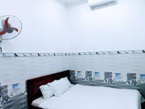 土龙木市Nhà nghỉ Đế Vương的卧室配有一张床,墙上配有风扇