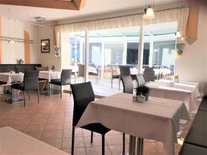 萨姆瑙恩奥罗拉加尔尼酒店的餐厅设有白色的桌椅和窗户。