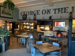 斯托克布里奇The George Inn Middle Wallop的餐厅设有桌椅,墙上有读书的标志